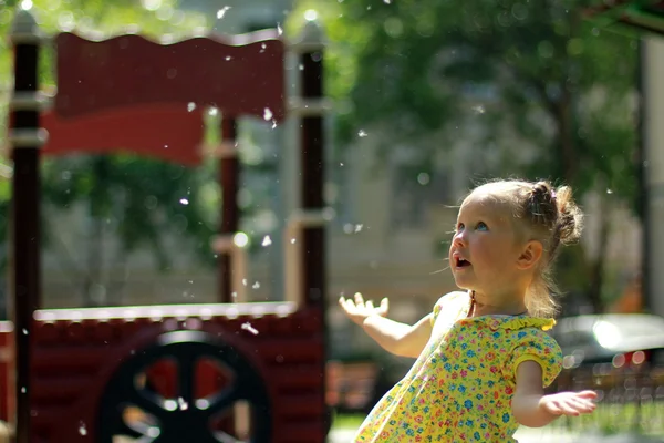 Little girl plays with poplar fluff — Stock Photo, Image