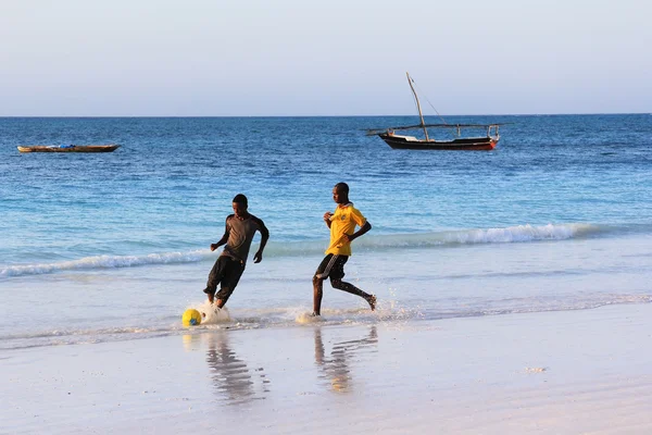 En fotballkamp på stranden ved solnedgang. – stockfoto