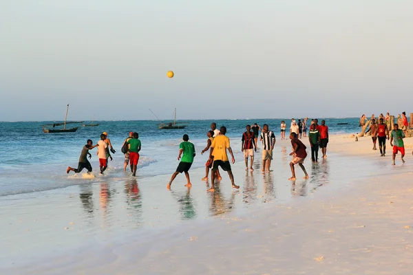 En fotballkamp på stranden ved solnedgang. – stockfoto