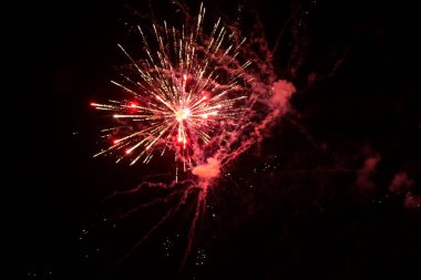 Siyah bir arka planda, kırmızı ışıklar ve duman saçan havai fişeklerin kıvılcımları.