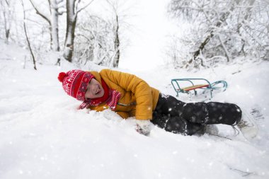 Oğlan bir kızakla tepeden düşerken düştü. Doğadaki çocuklar için kış tatili.