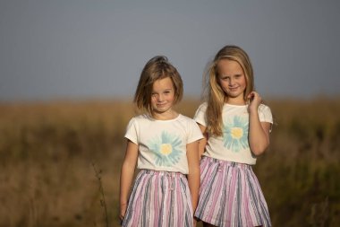 İki küçük kız bir yaz tarlasında duruyor. Kardeşlerim..