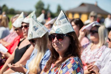 29 Ağustos 2020. Belarus, Lyaskovichi köyü. Şehir tatili. Kadın izleyiciler gazeteden şapka takıyor..