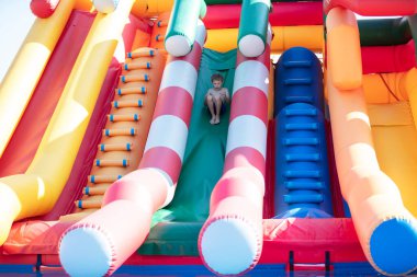 Çocuk şişirilebilir kaydırağın altına kayıyor..