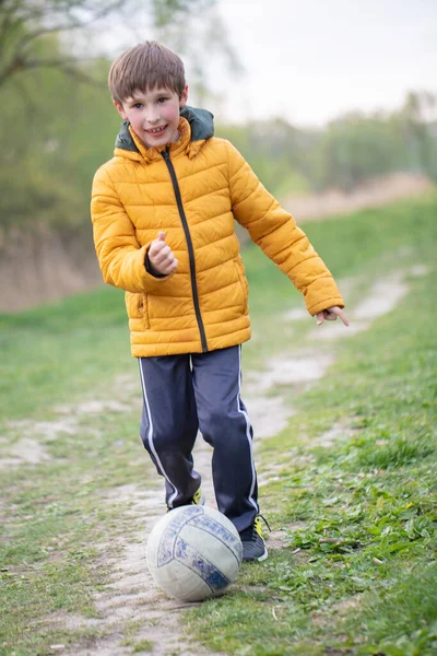 Un ragazzo in natura corre con un pallone da calcio. — Foto Stock