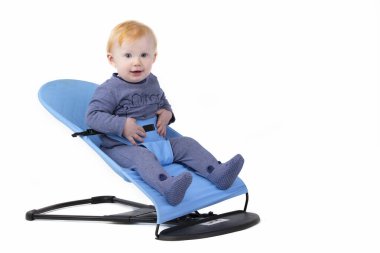 Yakışıklı bir çocuk beyaz bir arka planda bebek koltuğunda oturur..