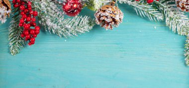 Turkuaz ahşap arka planda, ladin dalı ve koni süslemesi. Noel arkaplanı.