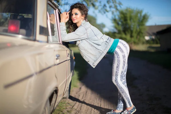 村の古い車の背景に面白いです若いです女性でザ デニムジャケットポーズ面白いです — ストック写真