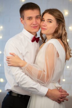 Gri arka planda, gelin ve damat birbirlerine bakıyorlar. Aşık güzel bir çift..