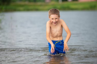 Küçük bir çocuk soğuk bir nehre doğru koşar. Çocuk yazın gölde yüzer..