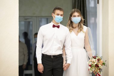 Gelin ve damat tıbbi maske takıyor. Koronavirüs salgını sırasında evlenmek..