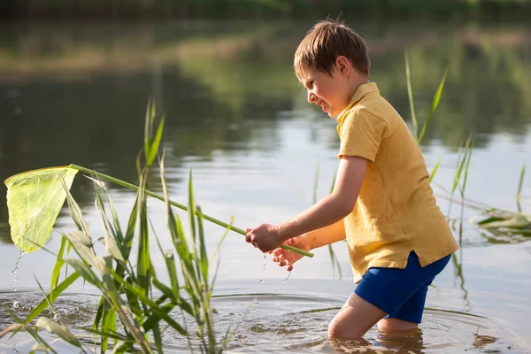 一个拿着蝴蝶网的小男孩在湖中钓鱼 — 图库照片