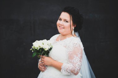 Koyu arkaplanda buketi olan bir gelinin portresi..