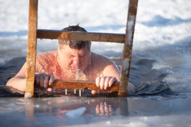 İsa 'nın vaftiz töreninde bir adam buz çukuruna dalıyor. Bir adam kışın buz çukurunda yüzer. Deniz aygırları..