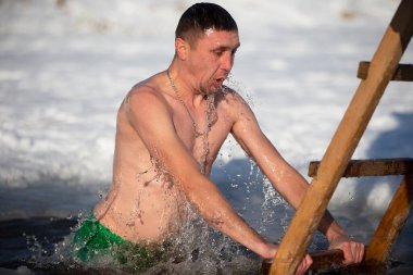 İsa 'nın vaftiz töreninde bir adam buz çukuruna dalıyor. Bir adam kışın buz çukurunda yüzer. Deniz aygırları..