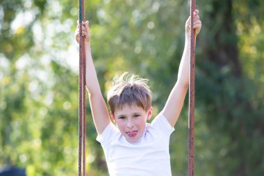 Çocuk yazın yeşilliğin arka planında salıncakta sallanıyor..
