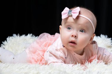 Siyah arka planda pembe elbiseli güzel bir kız. Bebek dört aylıkken. Komik bir çocuk..