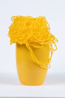 Büyük sarı bir kupa ve örgü iplikler..