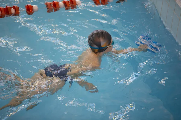 スイミングキャップの少年とプールでのスイミングゴーグル 子供は水泳部に従事している — ストック写真