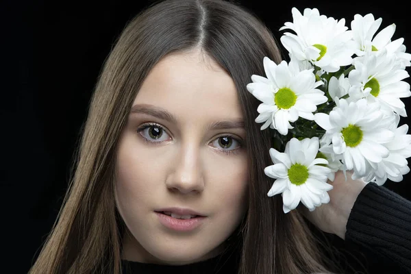一个美丽的小女孩 有着一头长长的光滑的秀发 手里拿着一束白菊花 — 图库照片