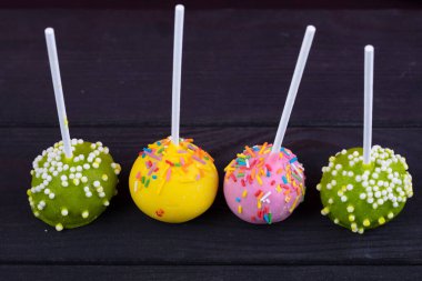 Siyah arka planda çubuk üzerinde çok renkli şekerler. Güzel tatlı bir tatlı..