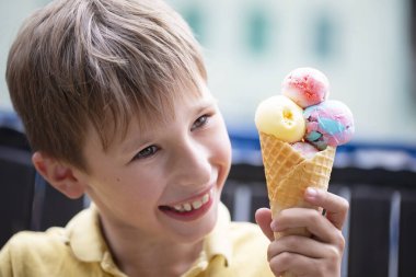 Küçük bir çocuk dondurma yiyor. Büyük porsiyon dondurması olan mutlu çocuk..