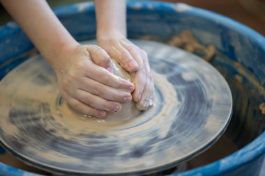 Bir çömlekçinin ellerine çömlekçinin tekerleğindeki bir nesneyle yakın çekim. Çamurla çalışmak. Clay atölyesi. Sanatsal eğitim.