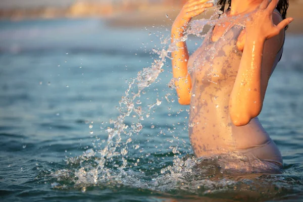 Tシャツを着た女性が海の水を噴き出す 海で泳ぐ — ストック写真