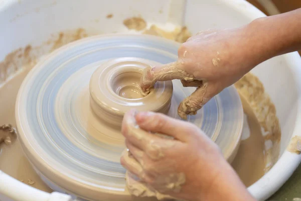 Close-up of a potter\'s hands with an item on a potter\'s wheel. Working with clay. Clay workshop. Craft training.