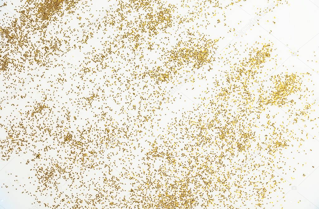 Festive or glamorous background. Gold sparkles scattered on a white background.