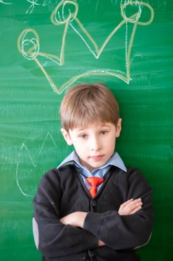 Komik çocuk tahtaya karşı. Taç desenli okullu çocuk.
