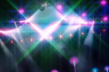 Işıklı ve mikrofonlu bir sahne. Işıklar yeşil ve mor. Sahnenin ortasında bir kişi var.