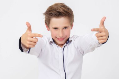 Beyaz gömlekli okul çağındaki bir çocuk parmaklarıyla bir başarı işareti gösteriyor..
