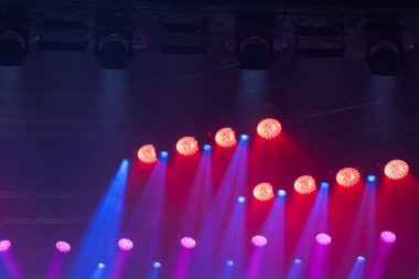 Kırmızı, mavi ve mor renkli bir sahne. Işıklar açık ve parlıyor.