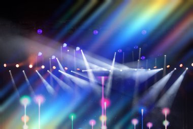 Koyu mavi arkaplanda çok renkli sahne ışığı demetleri.