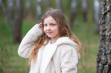 Uzun sarı saçlı mavi gözlü bir kızın portresi doğanın arka planında.