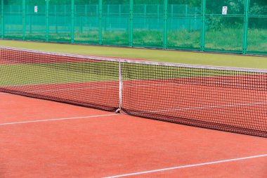 Tenis kortu boş. Ağları ve yeşil çitleri var..