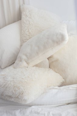 Yumuşak tüylü beyaz yastıklar yatağın üzerinde.