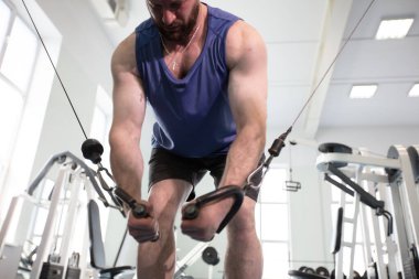 Erkek sporcu vücut geliştirici spor salonunda egzersiz yapıyor. Bir kablo makinesinde güç eğitimi.