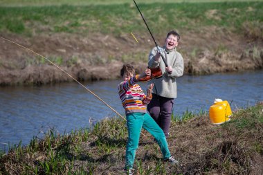 Balık tutmak eğlenceli. Çocuğun iki arkadaşı eski bir ayakkabıyı oltayla yakalamış ve gülüyorlar..