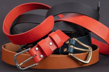 Koyu gri arka planda metal tokalı kırmızı deri kemerin bir parçası..