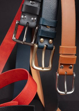 Koyu gri arka planda metal tokalı çeşitli deri kemerler..