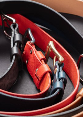 Koyu gri arka planda metal tokalı çeşitli deri kemerler..