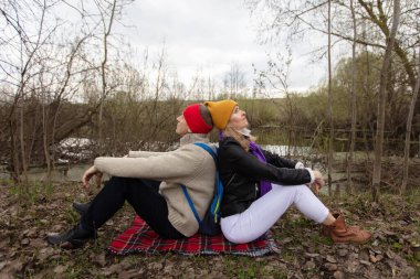 Bir erkek ve bir kadın, yaşlı bir çift, doğada bir turist pikniğinde dinleniyorlar. Sırt sırta verip oturuyorlar..