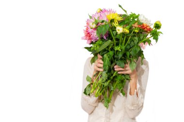 Beyaz bir arka planda elinde bir buket çok renkli yıldız çiçeği tutan tanınmayan bir kadın..