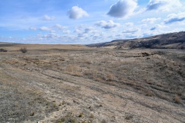 Dağlar, bozkırlar, çalılar, çimenler ve bulutlu gökyüzü. Bahar manzarası.