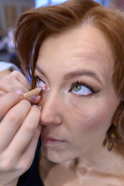 Yetenekli bir sanatçı, canlı bir güzellik salonunda güzellik ve sanatın özünü yakalayan bir makyaj uygulamasıyla müşterinin gözlerini güçlendirir..