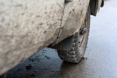 Yıpranmış bir off-road aracı zorlu yolları keşfettiği heyecanlı bir günün ardından çamurlu bir yüzeyde duruyor. Lastikleri çamurla kaplanmış, macerayı sergiliyor..