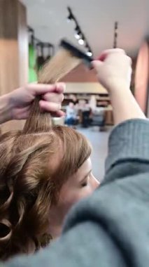 Yetenekli bir stilist bir güzellik salonunda sihirbazlık yapar, müşterinin güzel saçlarını dikkatlice kıvırır ve şekillendirir. Atmosfer canlı ve yaratıcı, eşsiz bir şımartma deneyimi sunuyor..