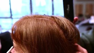 Yetenekli bir Japon stilisti canlı bir güzellik salonunda müşterinin saçı üzerinde ustaca çalışır. Şık bir saç stili oluşturuşuna dikkat edin..